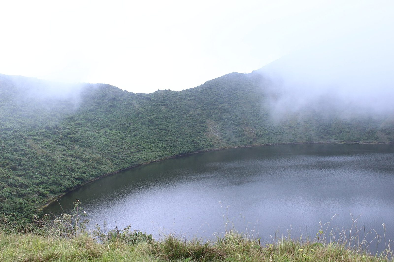 Hikers looking down into a green volcanic crater lake