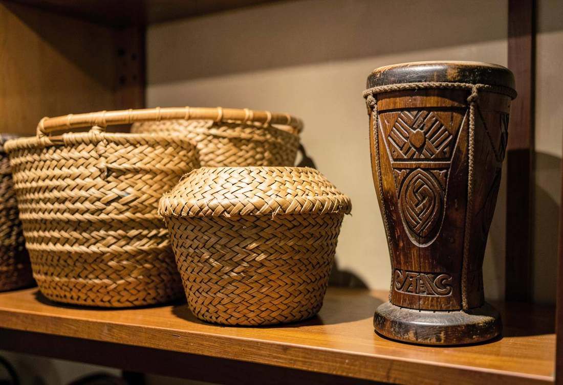 Woven Rwandan baskets and a carved royal drum on a museum shelf
