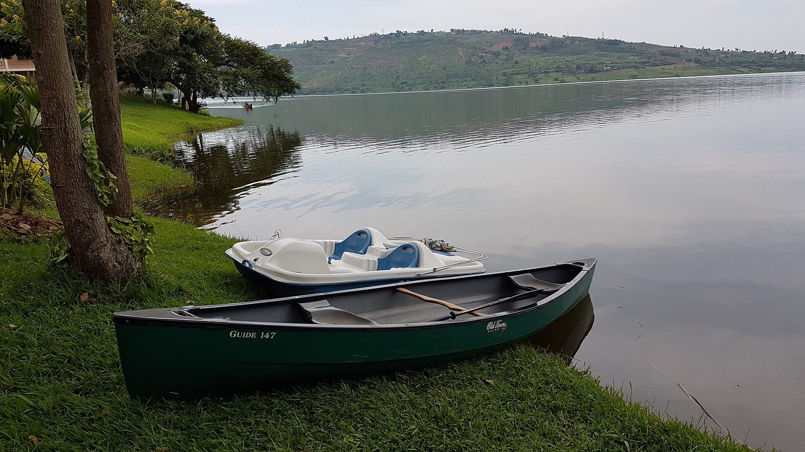 Wooden boats on a calm lake with green hills behind